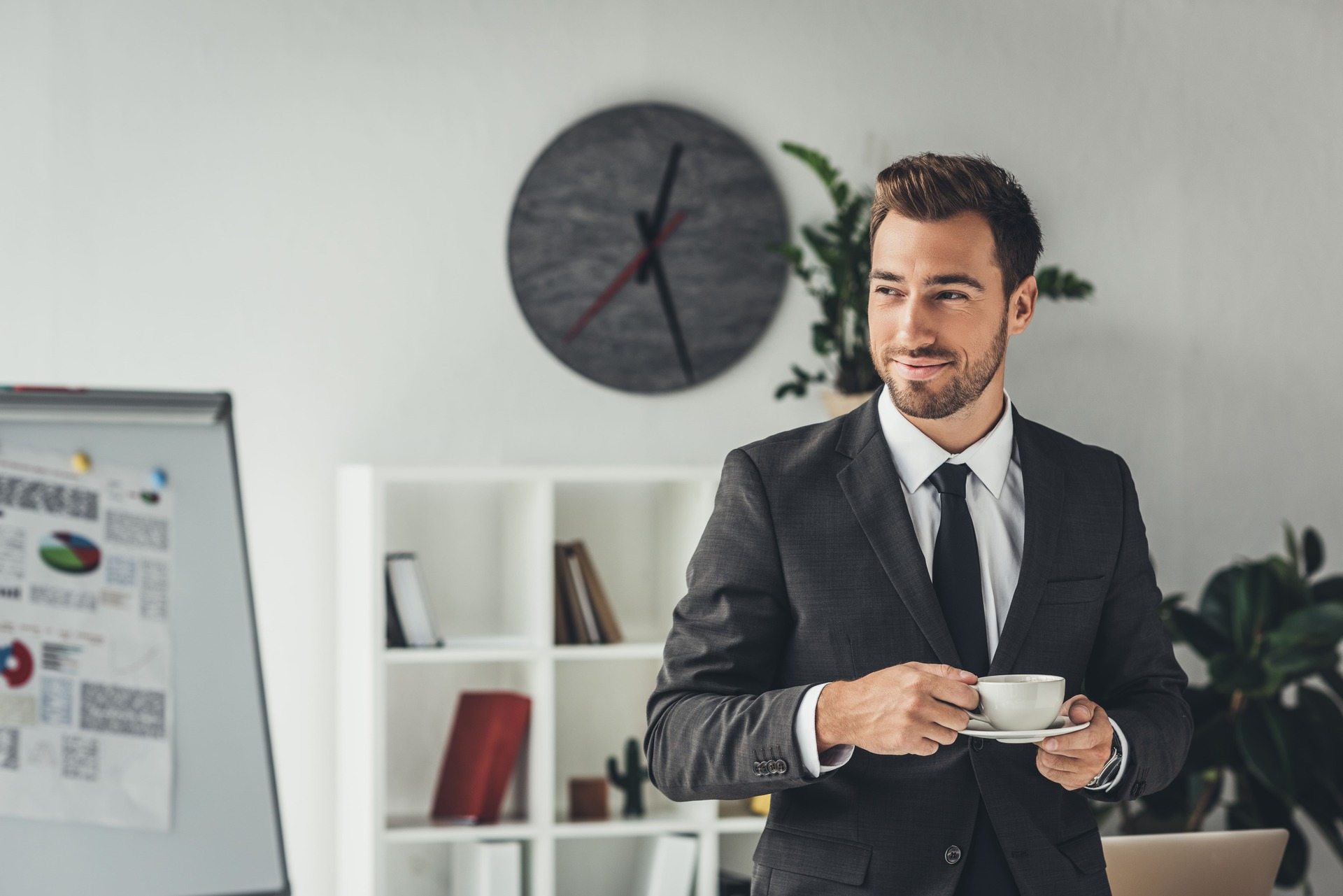 happy-young-businessman-with-cup-of-coffee-at-offi-JB7JNZ8.jpg